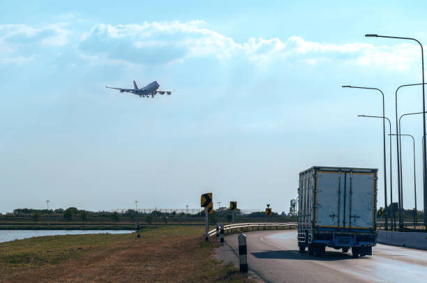 Flying passenger jet plane on the sky over the container truck running on the road, transport and logistic concept.